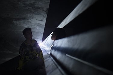 Two people stand in a "solid light" sculpture