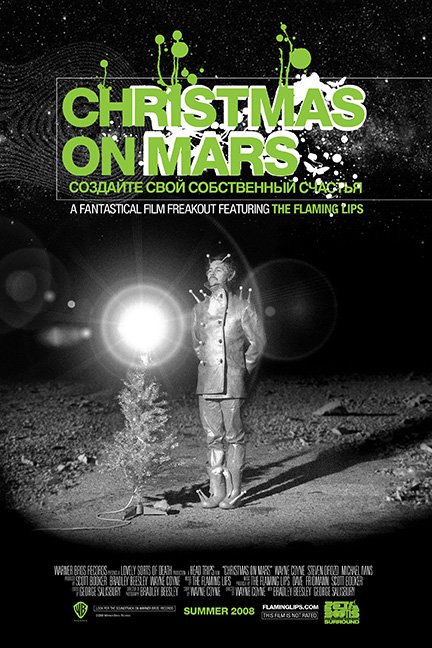 Black and white poster of a humanoid alien standing next to a small Christmas tree on barren terrain