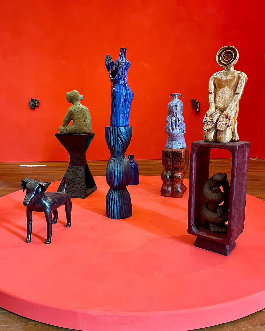 Humanoid and animal-like sculptures on a red plinth