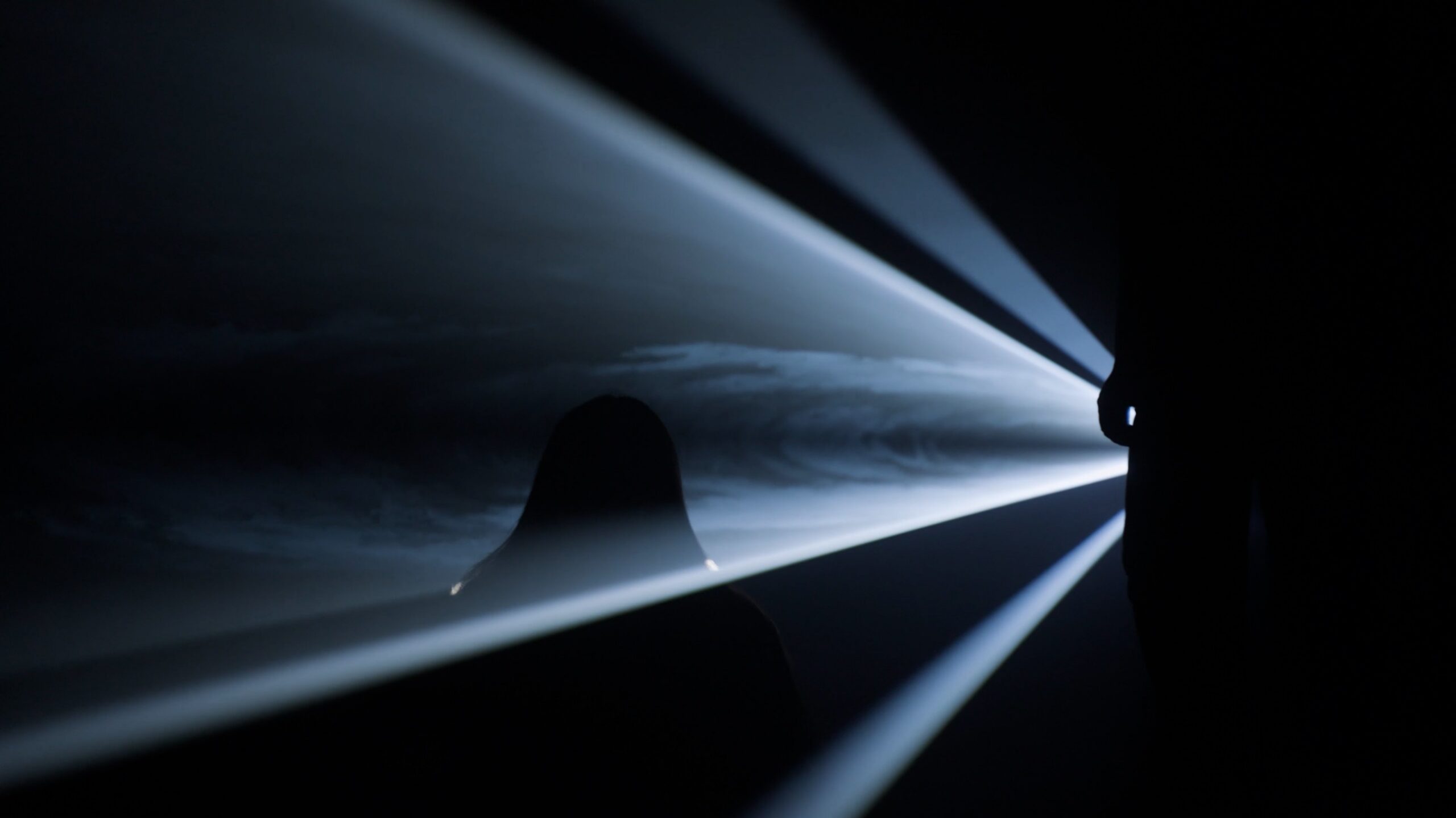 Two people interact with beams of light in a dark room