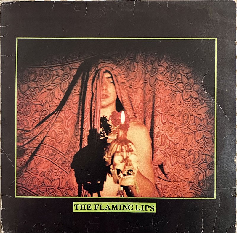 An album cover with a man holding a skull topped with a candle