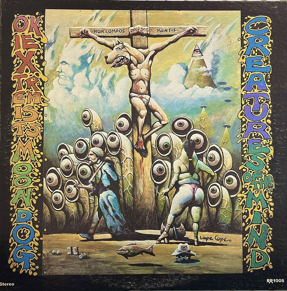 A person with a dog head on a crucifix surrounded by eyballs on stalks, cows being lifted by UFO beams, and a pyramid topped with an eye